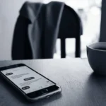 Smartphone on a table showing a text message with “BBL,” visually explaining what does BBL mean in texting in a real-life chat setting.