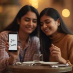 Two women sitting in a café smiling while showing a phone screen that reads “Je t’aime,” illustrating what does je t’aime mean in real-life conversation.