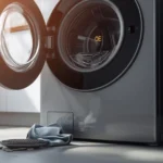 Modern front-load washing machine displaying OE error code on the screen, with open drain filter, towel, and coins on the floor indicating a drainage issue.