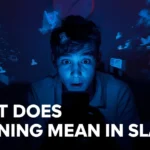 Young man sitting in a dark room at night, illuminated by the blue glow of his smartphone with social media icons and notifications floating around him, and text reading “What Does Gooning Mean in Slang?” representing digital overstimulation and online obsession.