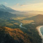 Region landscape showing snow-capped mountains, fertile farmland divided by a river, and a coastal shoreline at sunset illustrating distinct geographic regions within one area